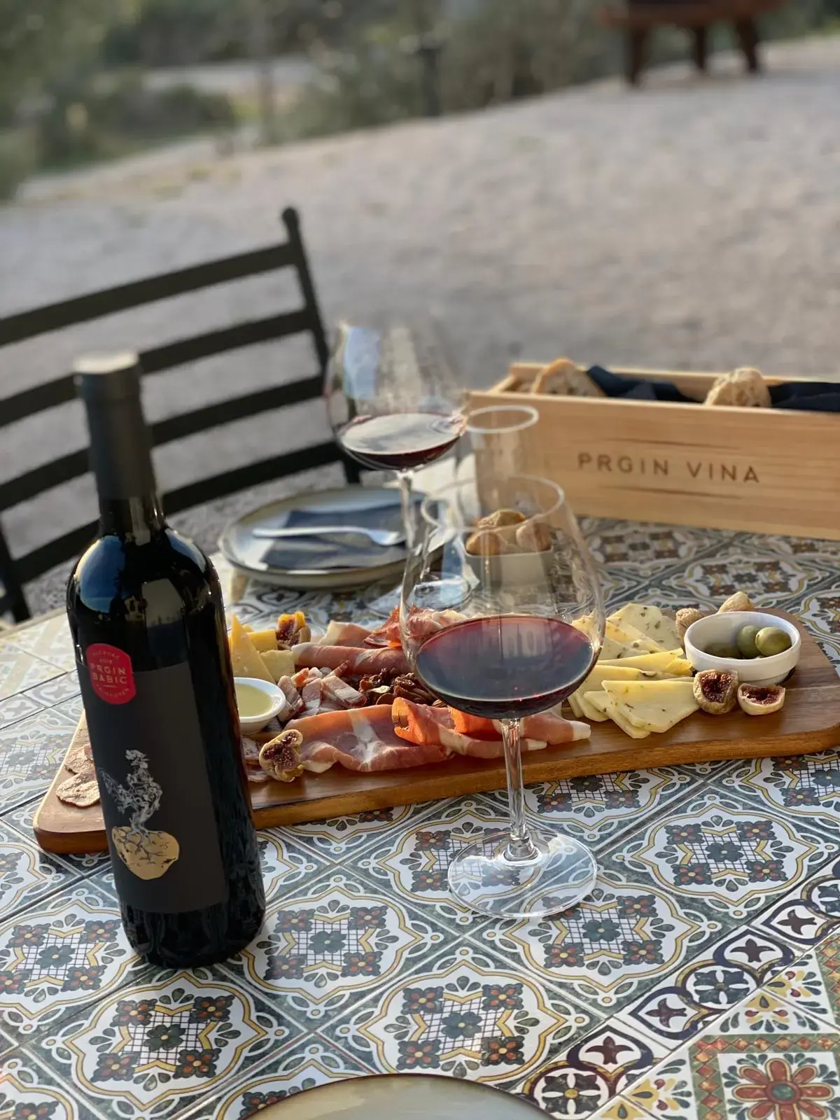 Babić wine on the table next to some prosciutto and cheese.