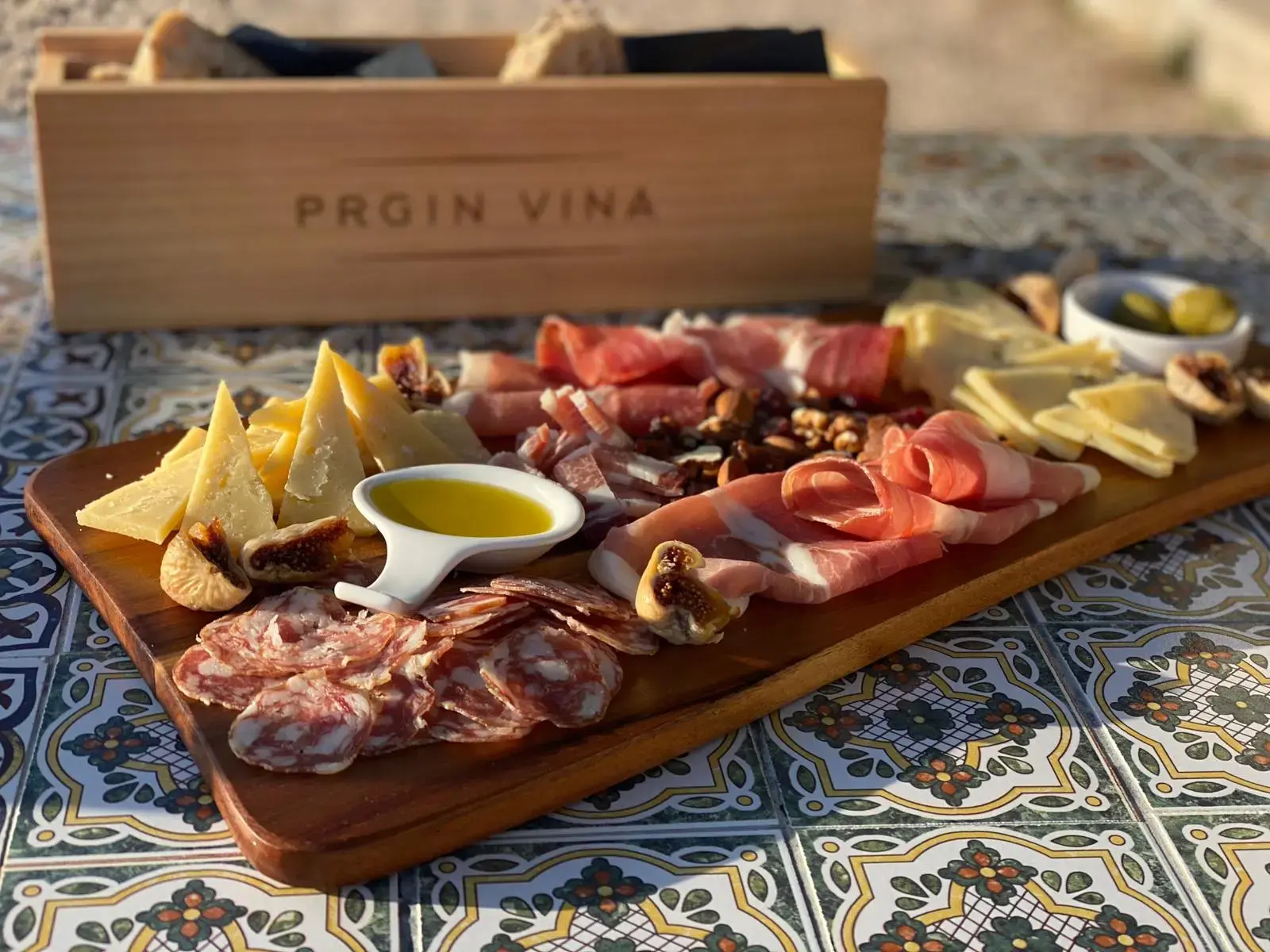 Different food on a wooden board, ham, cheese, olives.